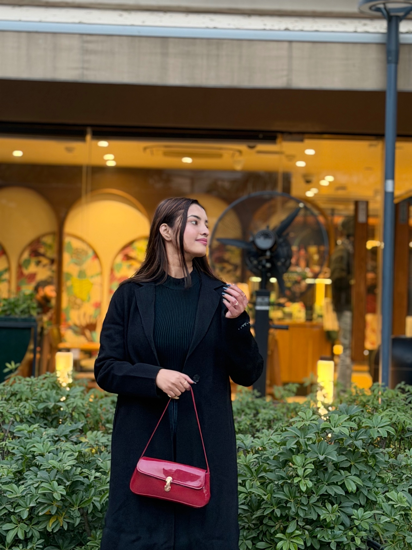 Pragati Gupta in a black wool coat outside a café